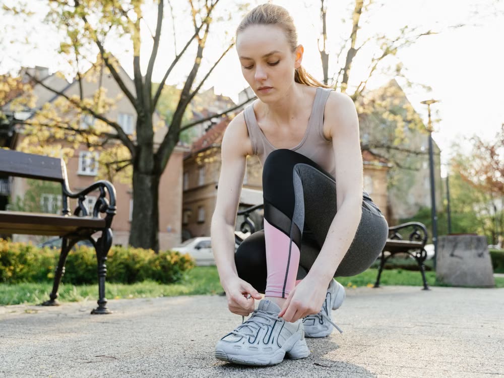 Woman tying running shoes outdoors before exercise.